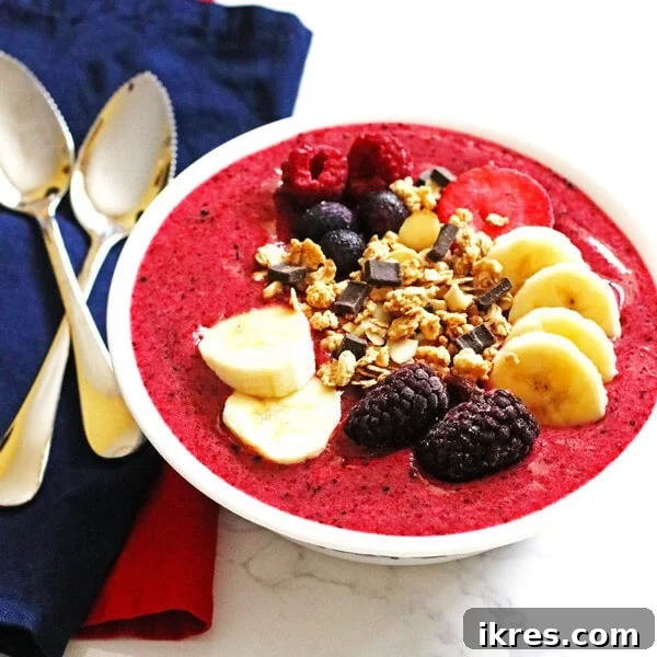 Berry Banana Bliss Bowl 4 A perfectly blended pink berry banana smoothie bowl, generously adorned with vibrant banana slices, whole fresh berries, and crunchy granola, ready to be savored.