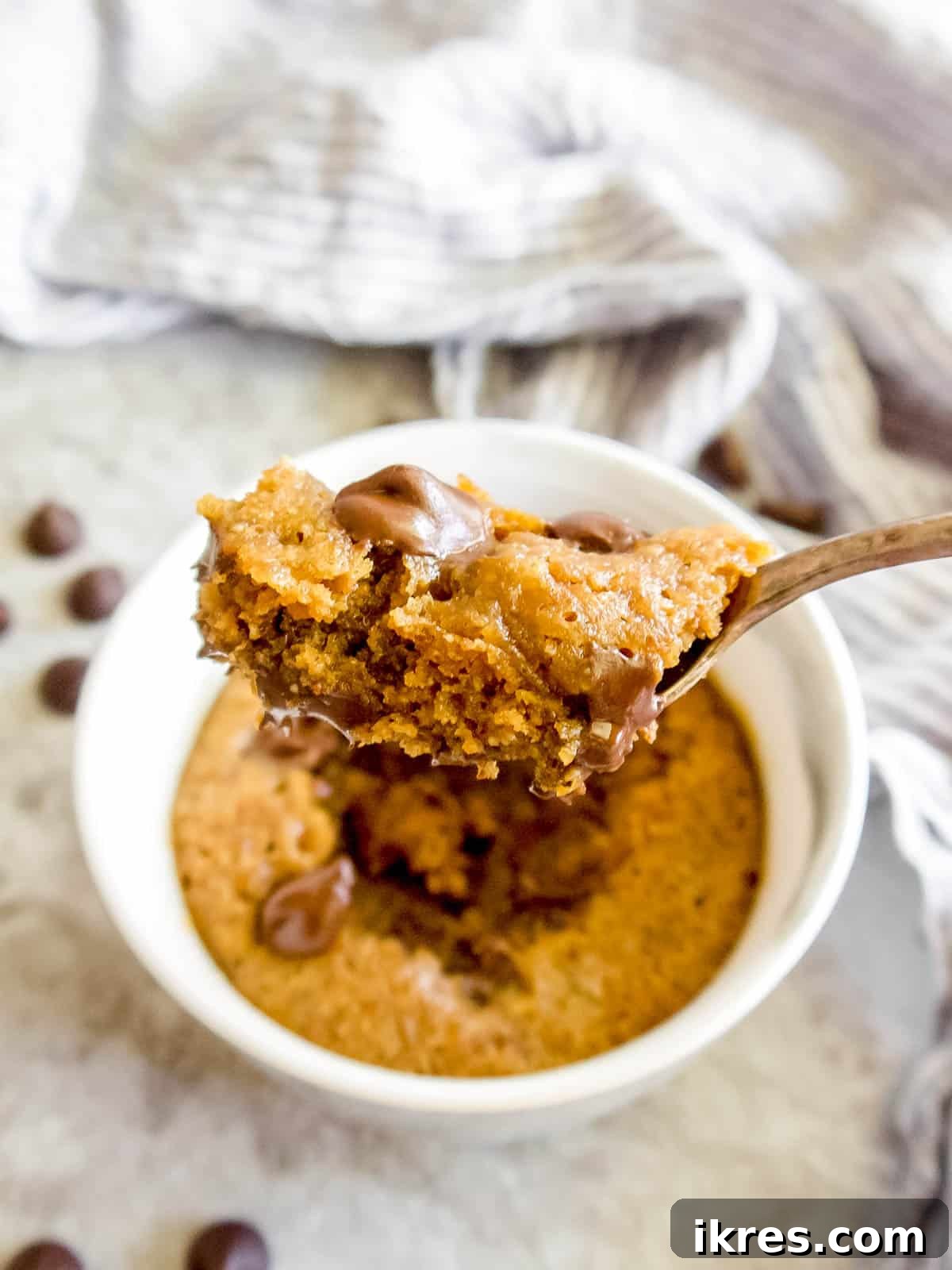 Guilt-Free Paleo Mug Cookie Delight 3 A spoon with a bite of a healthy, Paleo mug cookie, showing its soft texture and chocolate chunks.