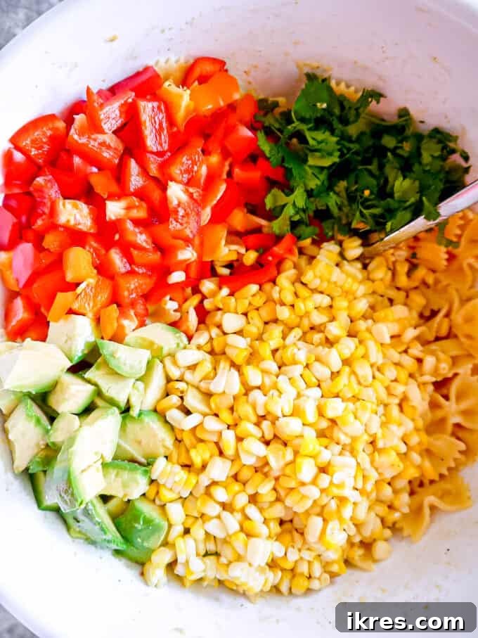 All of the ingredients on top of the pasta salad, vibrant and colorful.