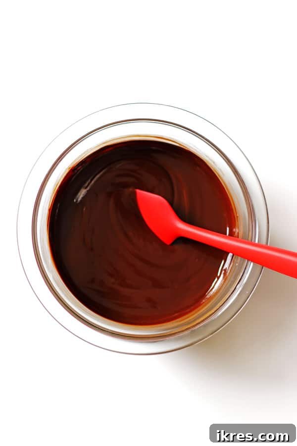 Ultimate Homemade Brownies 5 Smooth, melted butter and semi-sweet baking chocolate in a clear bowl, with a red spatula for stirring.