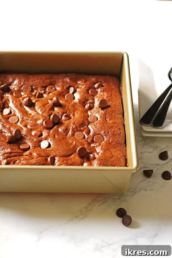 Ultimate Homemade Brownies 8 Freshly baked brownies in a square pan, showing a slightly crinkled top, with melted chocolate chips visible.
