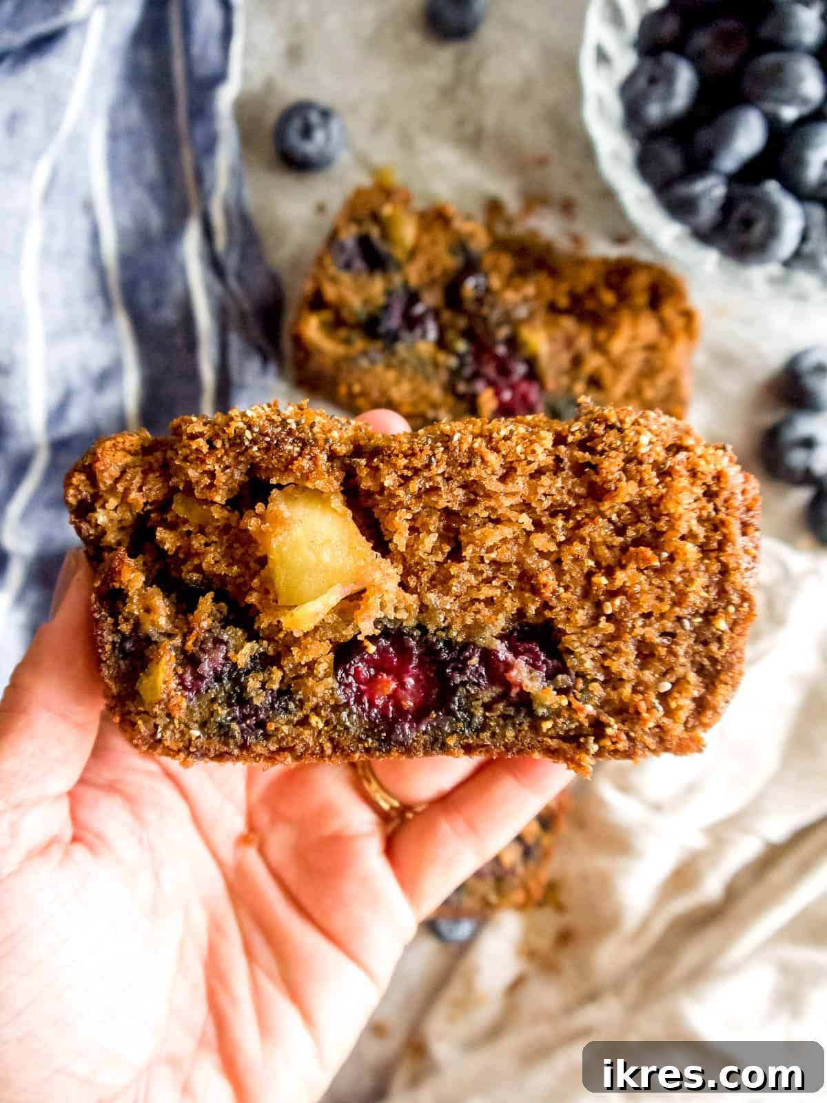 A comforting loaf of blueberry bread made with almond flour, held gently in hands.