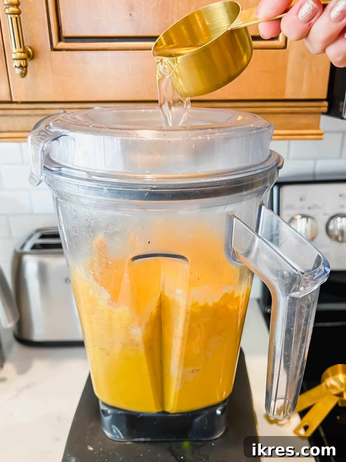Water being poured into the blender while the hummus is mixing.