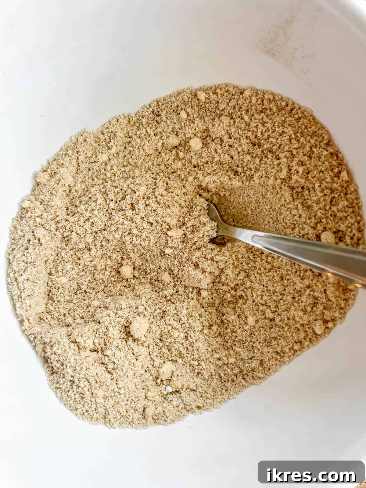 Artisanal Pumpkin Olive Oil Cake 6 A bowl filled with the precisely measured dry ingredients for the pumpkin olive oil cake, showcasing almond flour, coconut flour, baking powder, baking soda, salt, cinnamon, and pumpkin pie spice.