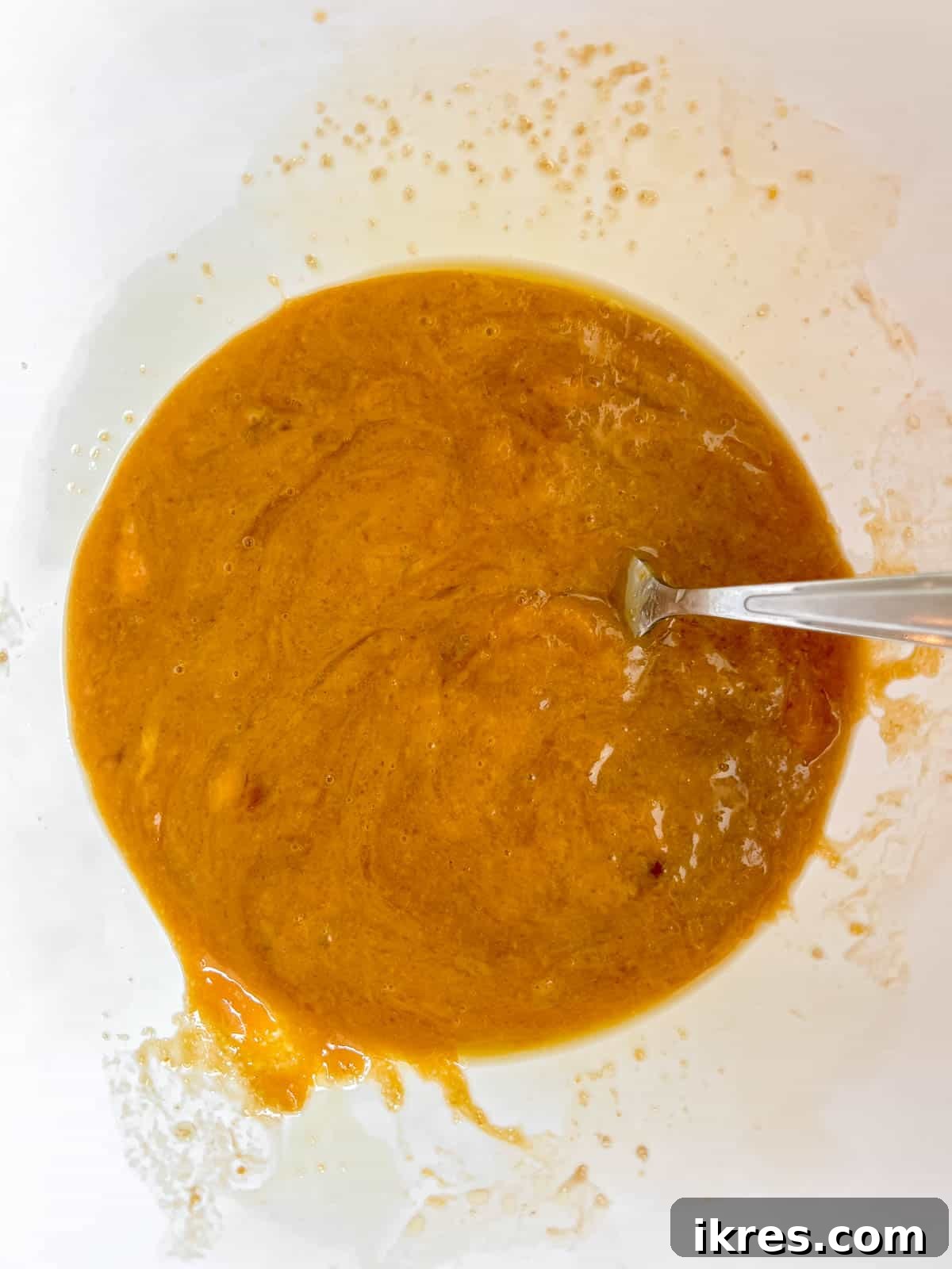 Artisanal Pumpkin Olive Oil Cake 7 A separate bowl holds the wet ingredients for the pumpkin olive oil cake, including olive oil, eggs, brown sugar, pumpkin puree, and vanilla extract, all ready to be mixed.