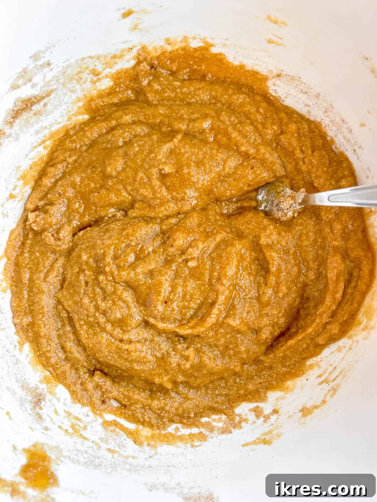 Artisanal Pumpkin Olive Oil Cake 8 The combined wet and dry ingredients for the pumpkin olive oil cake are shown in a bowl, having been mixed thoroughly to form a smooth batter.