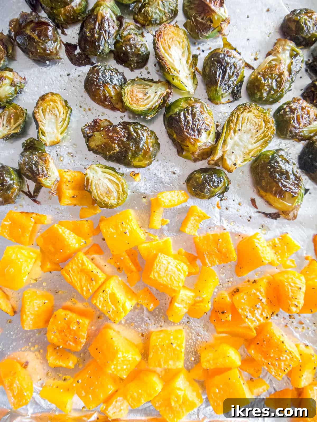 Close-up of roasted brussels sprouts and butternut squash on a baking sheet, golden and caramelized.