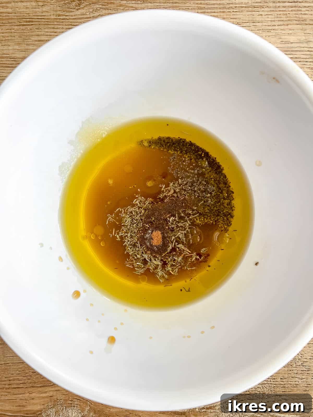A small bowl filled with the amber-colored maple vinaigrette dressing, ready to be tossed with the salad.