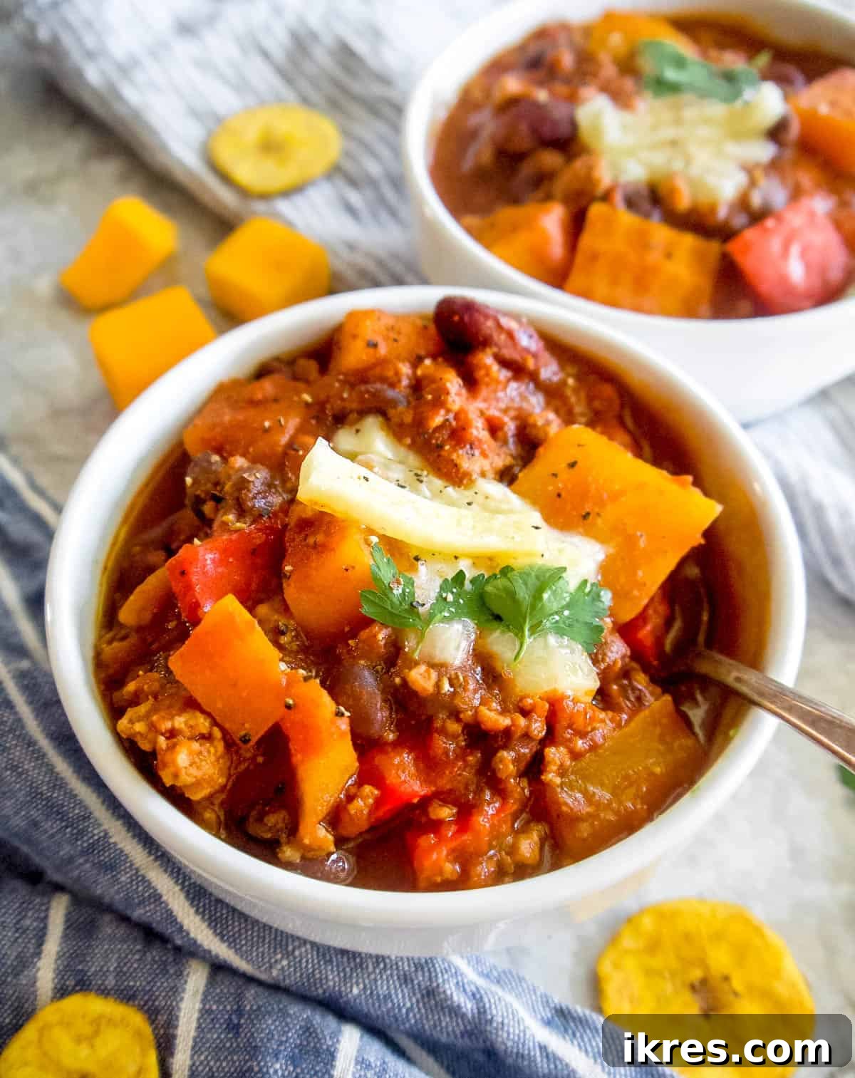 Hearty Turkey Chili with Butternut Squash and Black Beans 2 A steaming bowl of Butternut Squash Turkey Chili, generously topped with shredded cheese and fresh herbs, ready to be enjoyed.