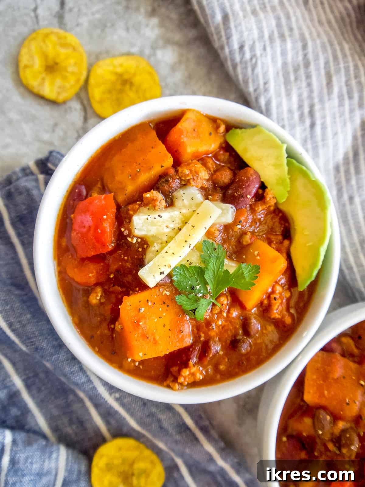Hearty Turkey Chili with Butternut Squash and Black Beans 11 Two bowls of inviting butternut squash chili with ground turkey, garnished with fresh herbs, ready for a comforting meal.
