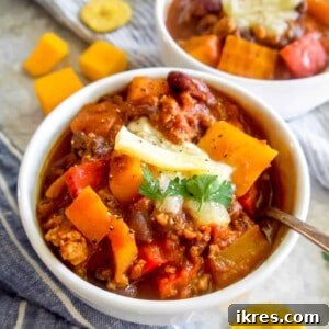 Butternut Squash Turkey Chili in a bowl with cheese on top.