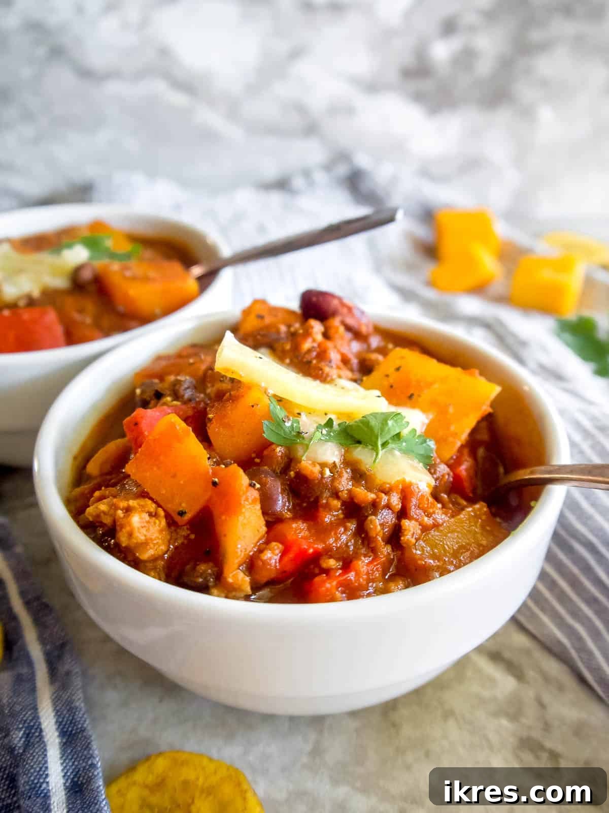 Hearty Turkey Chili with Butternut Squash and Black Beans 10 Butternut squash and black bean chili served in two rustic bowls, beautifully garnished and ready to be enjoyed, showcasing its hearty texture.