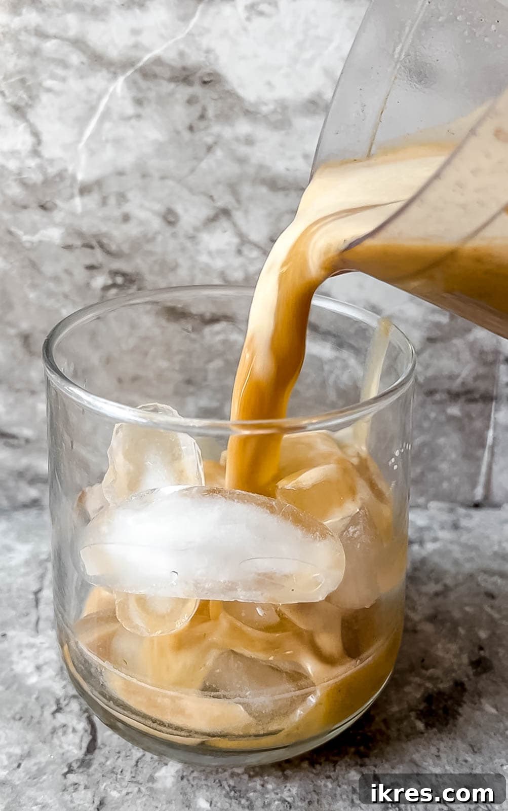 Pouring a perfectly blended pumpkin spice white Russian into a glass filled with ice.