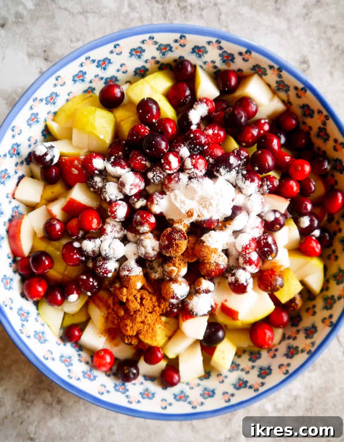 Spiced Pear Cranberry Crisp 5 Cut up pear and cranberries mixed with spices in a baking dish.