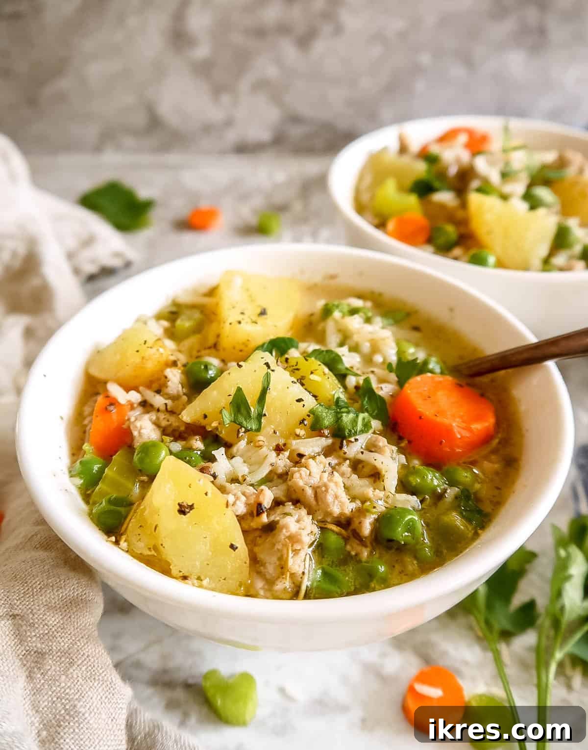 Ground turkey rice soup served in two rustic bowls with spoons.