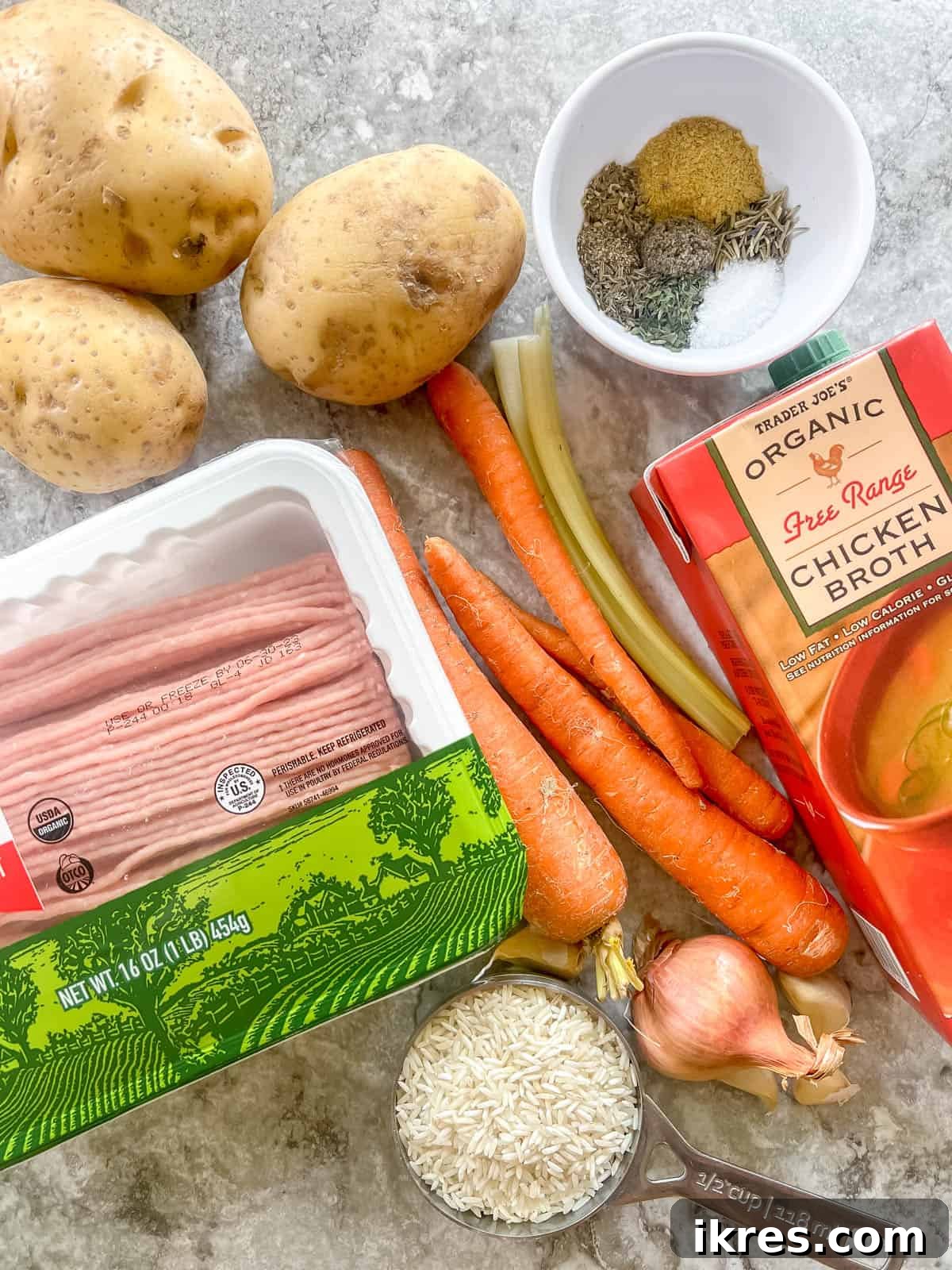 A flat lay photo of all the fresh ingredients needed to make ground turkey soup with rice, including vegetables, herbs, and ground turkey.