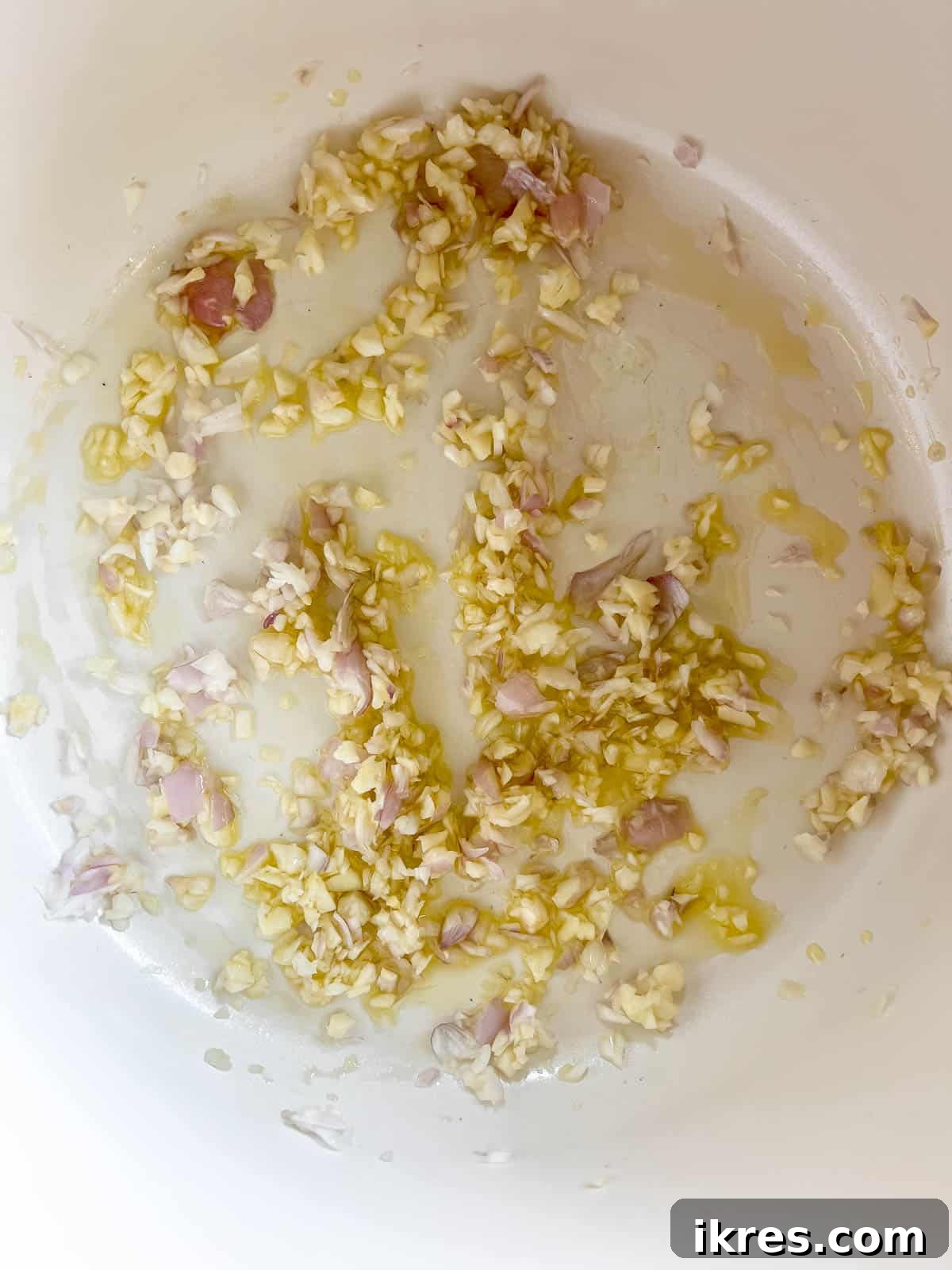 Sautéing minced shallot and garlic in olive oil in a large soup pan.