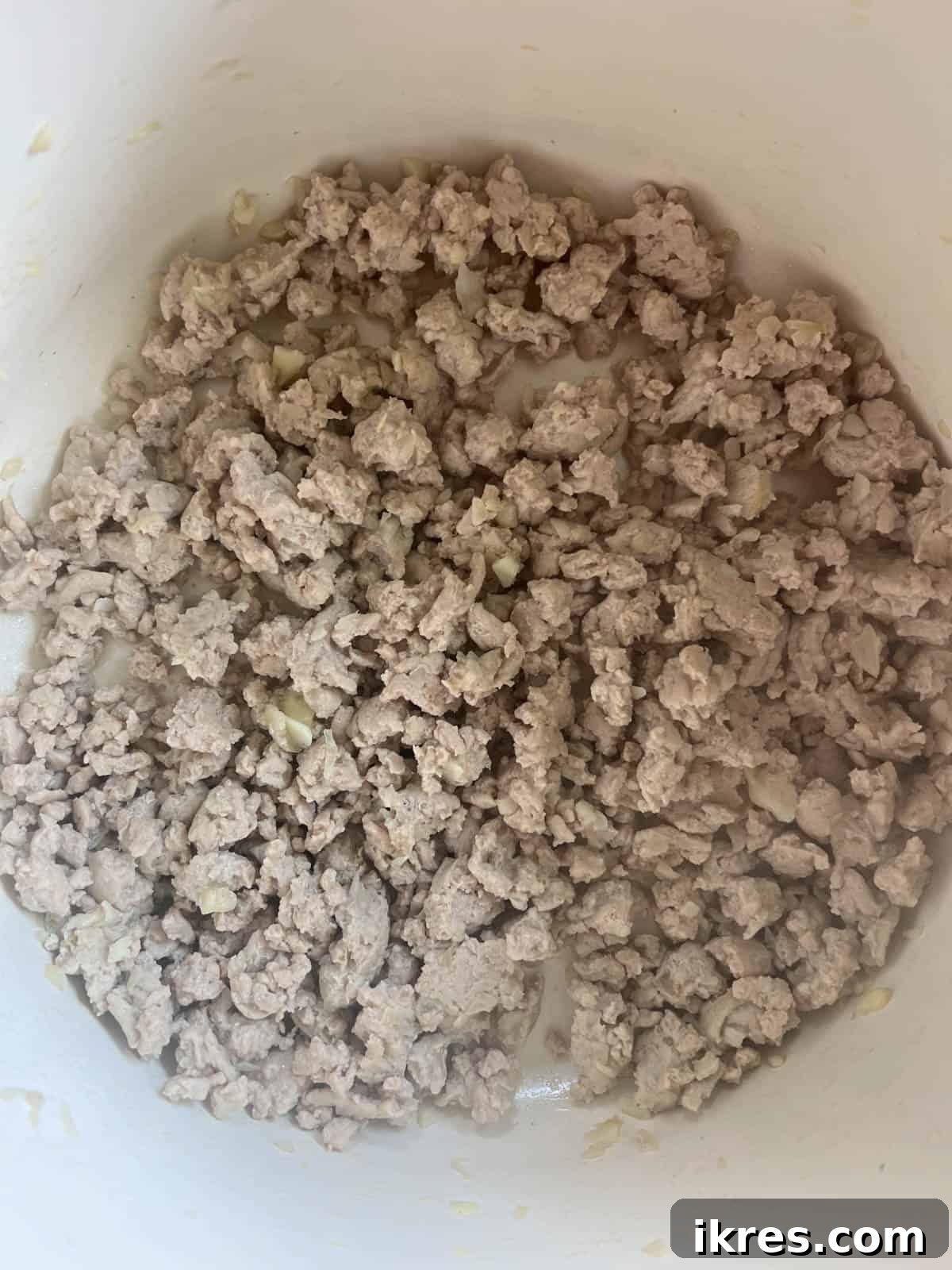 Browning ground turkey in a pan with shallots and garlic.