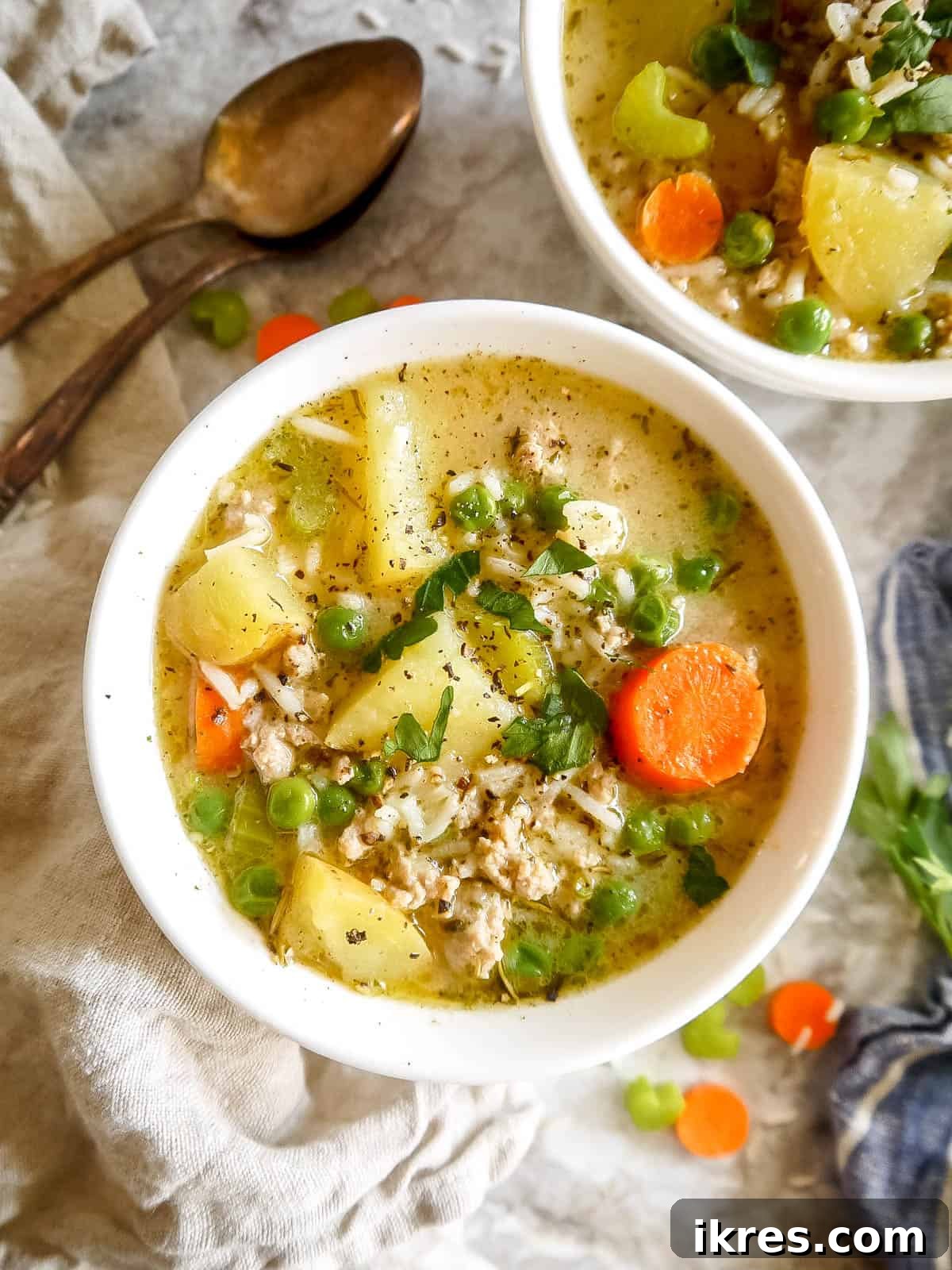 Creamy turkey and rice soup served in two bowls, garnished with fresh herbs.