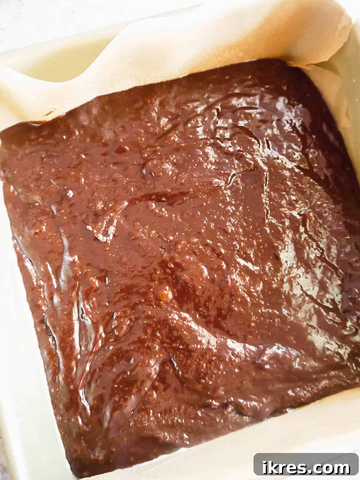 Deliciously Wholesome Almond Flour Brownies 11 Smooth brownie batter poured evenly into a parchment-lined square baking tin.