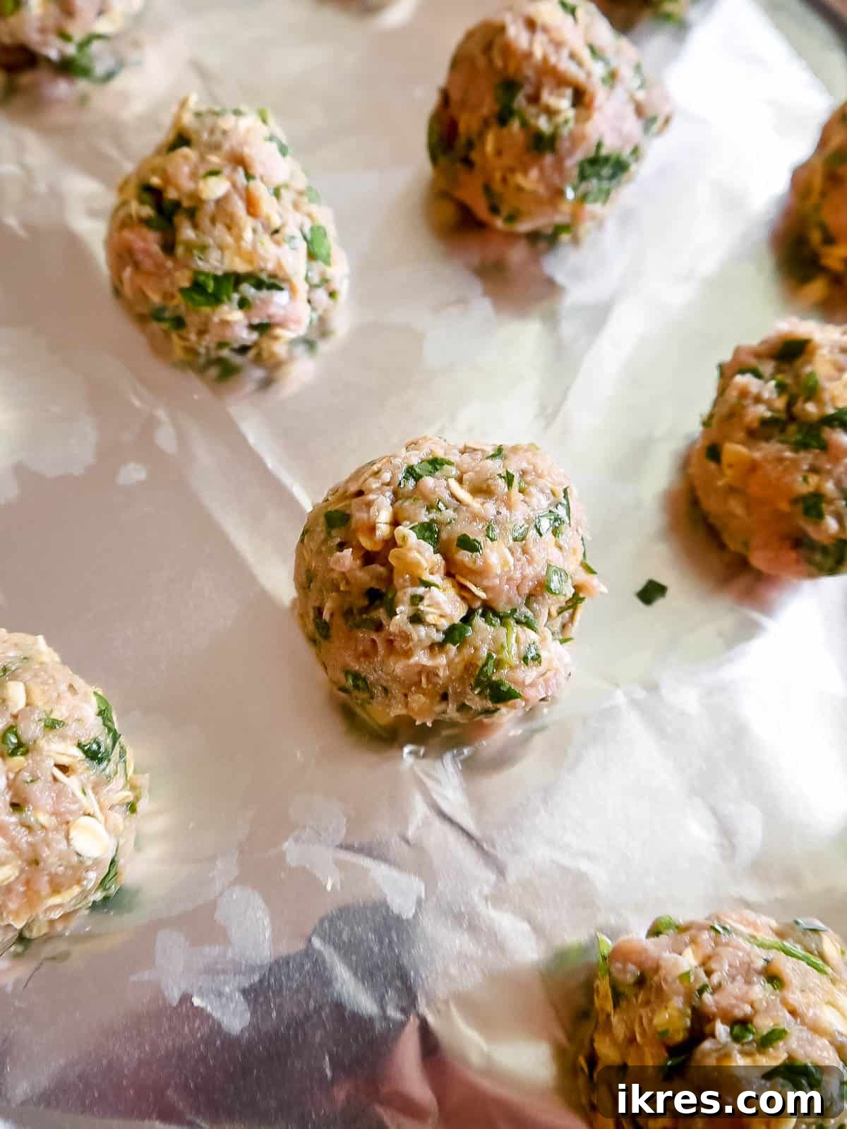 Lean & Green Baked Turkey Spinach Meatballs (Gluten-Free) 5 Turkey spinach meatballs rolled and ready for baking on a lined tray.