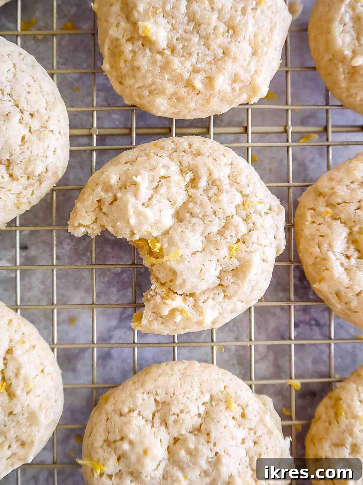 A close-up of a lemon sugar cookie with a bite taken out, showing its soft and chewy texture.