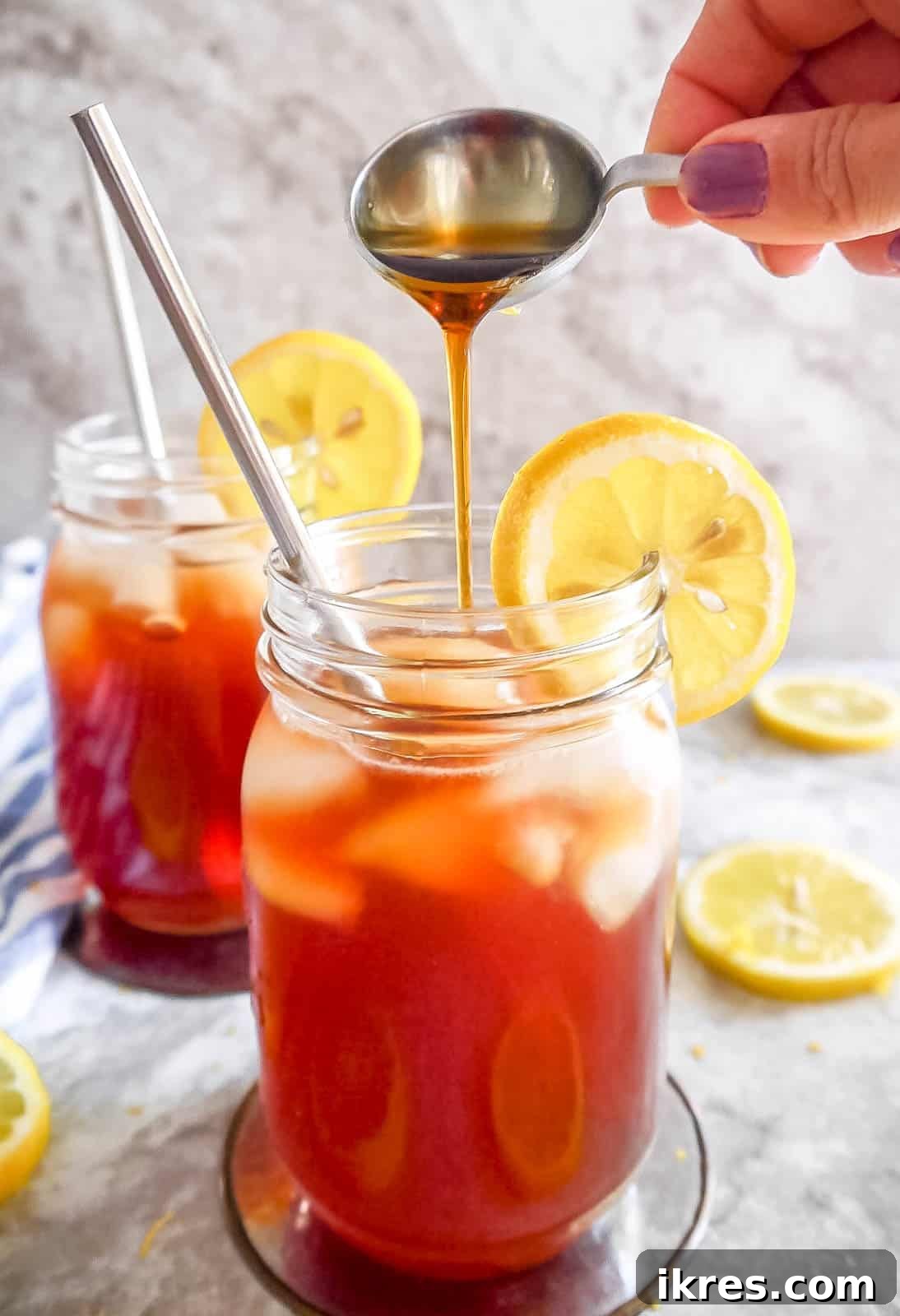 Maple syrup being poured into a glass of healthy sweet tea, highlighting the natural sweetener.
