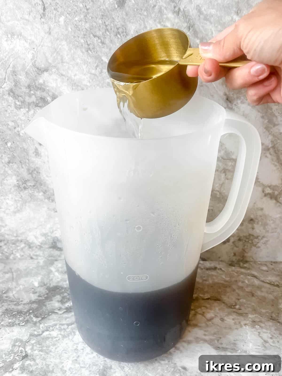 Cold water being added to the sweetened tea concentrate in a pitcher.