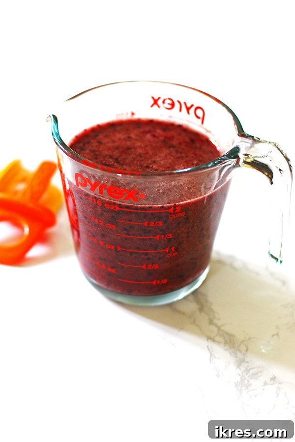 Smooth blueberry lemon popsicle mixture in a clear Pyrex measuring cup with a spout, ready for pouring into molds.