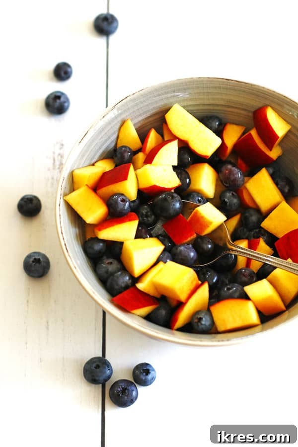 Fresh blueberries and sliced peaches in a grey bowl, illustrating a simple, healthy snack idea.