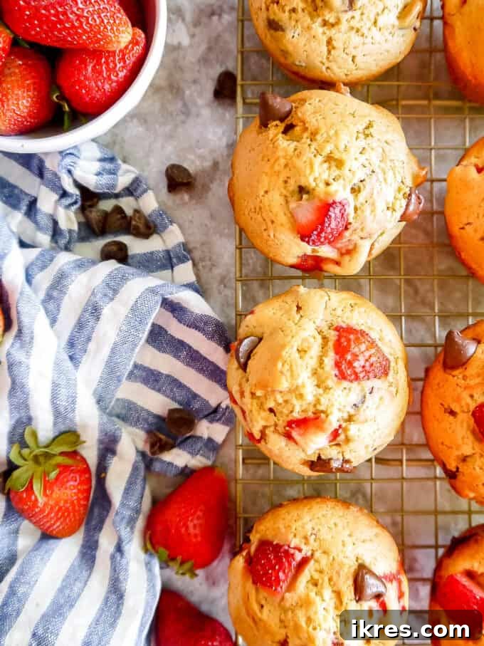 strawberry chocolate chip muffins cooling off on a wire rack, with a rustic kitchen background