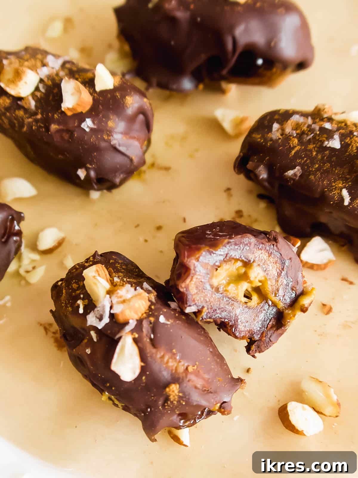 Close-up of pumpkin dates cut in half, surrounded by crushed almonds, highlighting the rich filling.