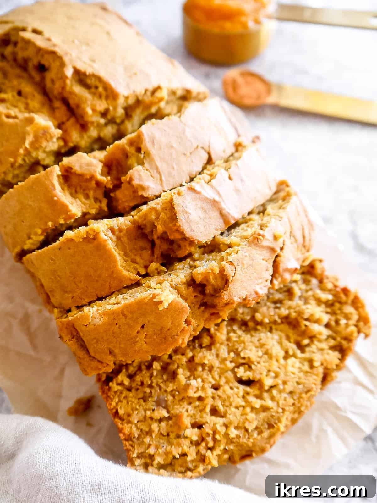 A side angle view of a loaf of healthy pumpkin banana bread, showcasing its beautiful crust and moist interior.