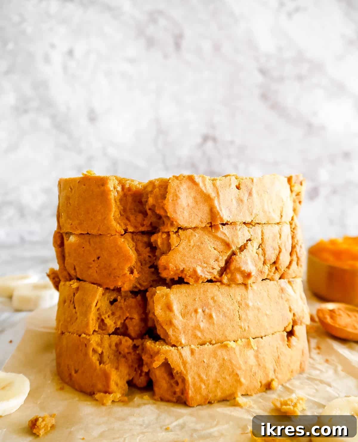 Several stacked slices of moist pumpkin banana bread, highlighting its soft texture.
