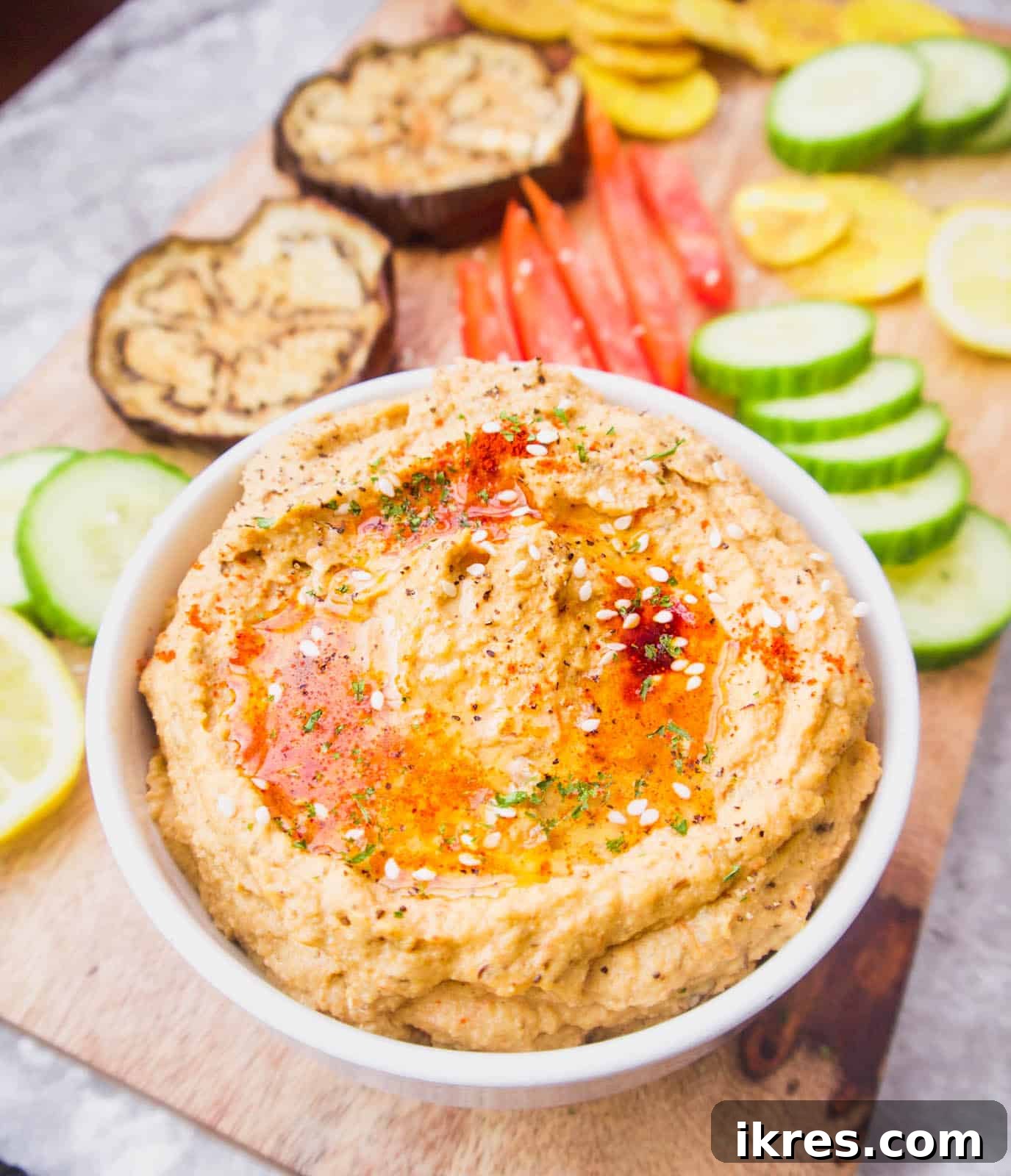 A vibrant bowl of chickpea-free hummus surrounded by an assortment of fresh raw vegetables like carrots, cucumbers, and bell peppers, perfect for dipping.