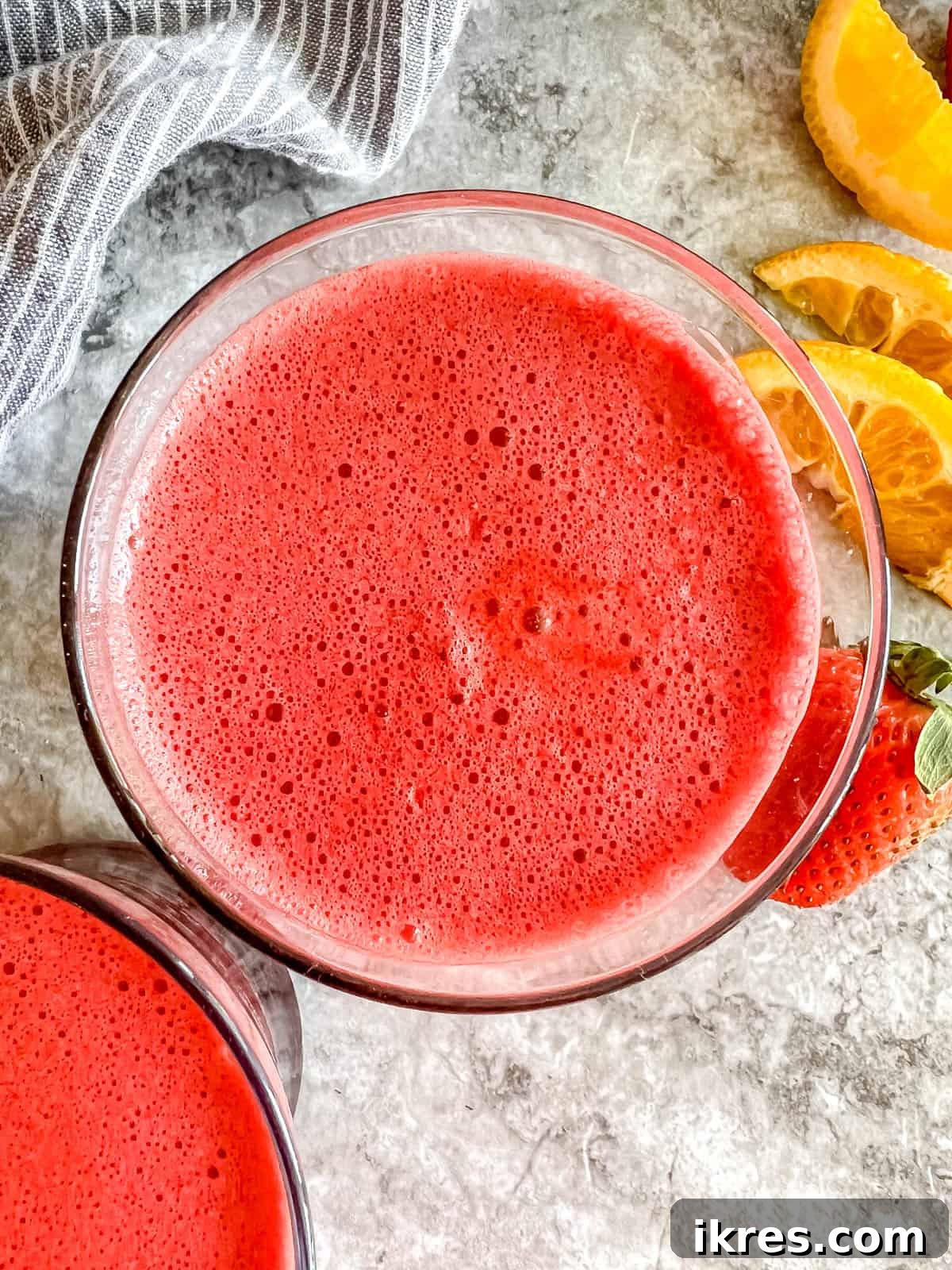 Vibrant Root Nectar 3 An aerial view of the vibrant strawberry, beet, orange, and carrot juice in a glass, surrounded by fresh ingredients.