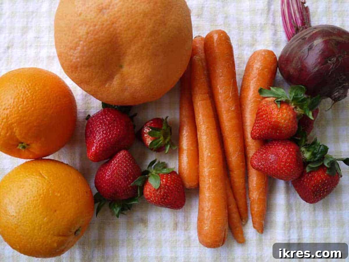 Vibrant Root Nectar 4 Fresh ingredients laid out on a table: grapefruit, oranges, strawberries, carrots, and beetroot, ready for making strawberry beet orange carrot juice.