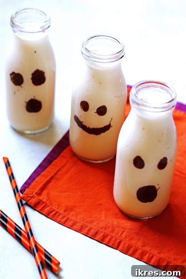 Monster Milkshake Creations 4 Close-up of a clear glass filled with vanilla milkshake and topped with whipped cream, ready for serving as a Halloween Ghost Milkshake.