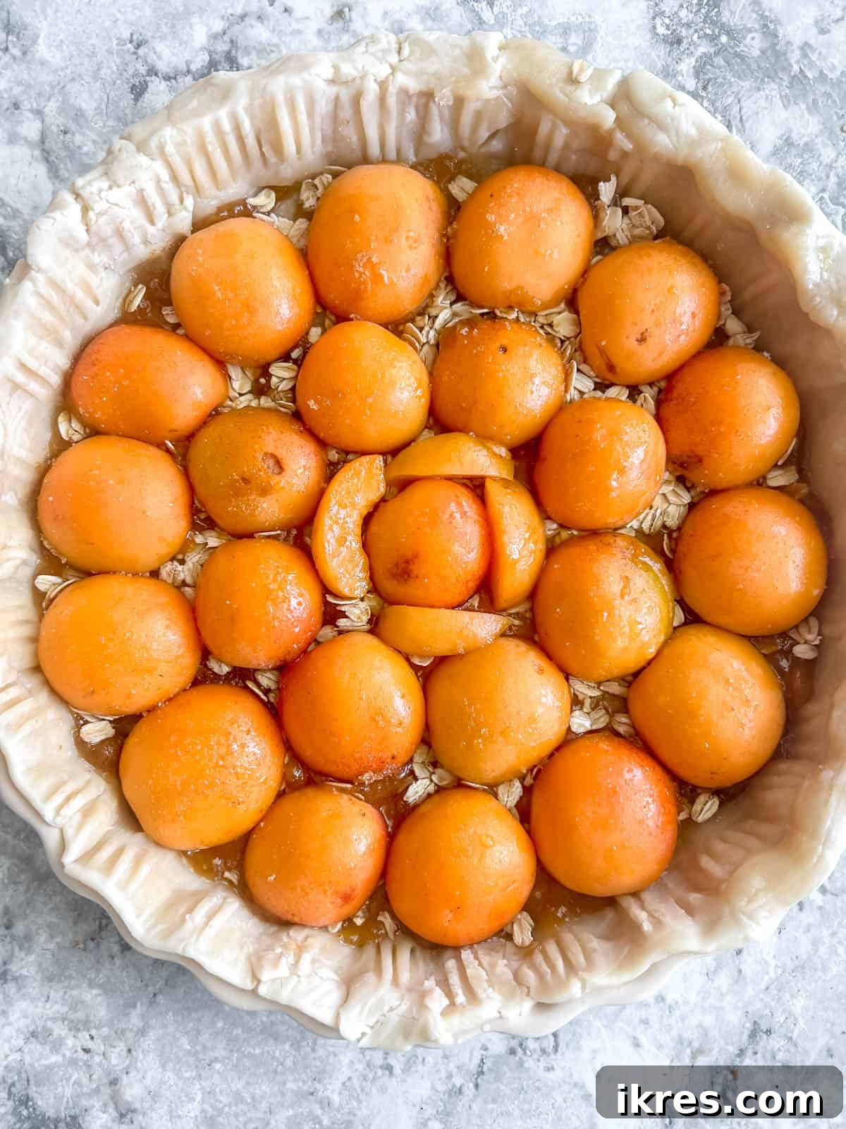 No-Fuss Apricot Tart with Premade Pastry 7 A layer of rolled oats sprinkled over the jam, followed by halved apricots arranged neatly on top.
