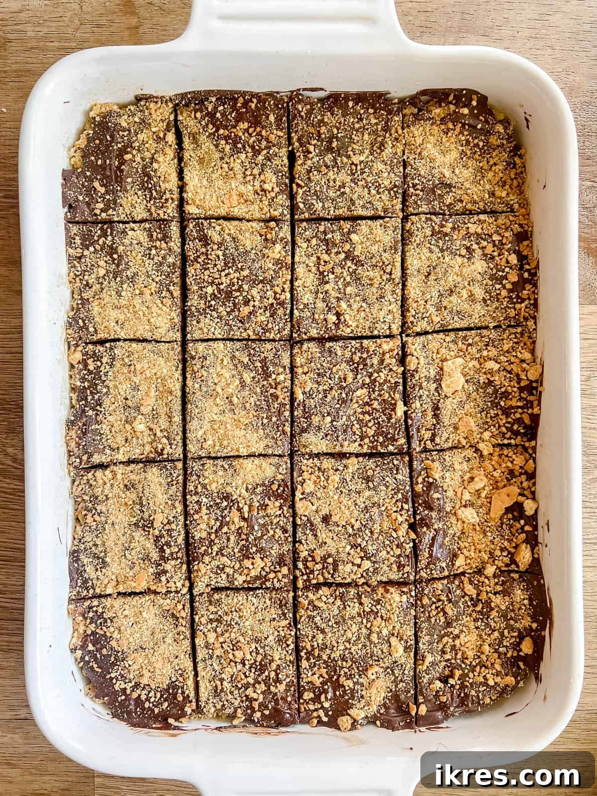 A full pan of S'mores Rice Krispie Treats, perfectly set with chocolate and graham cracker topping, scored and ready to be cut into individual squares.