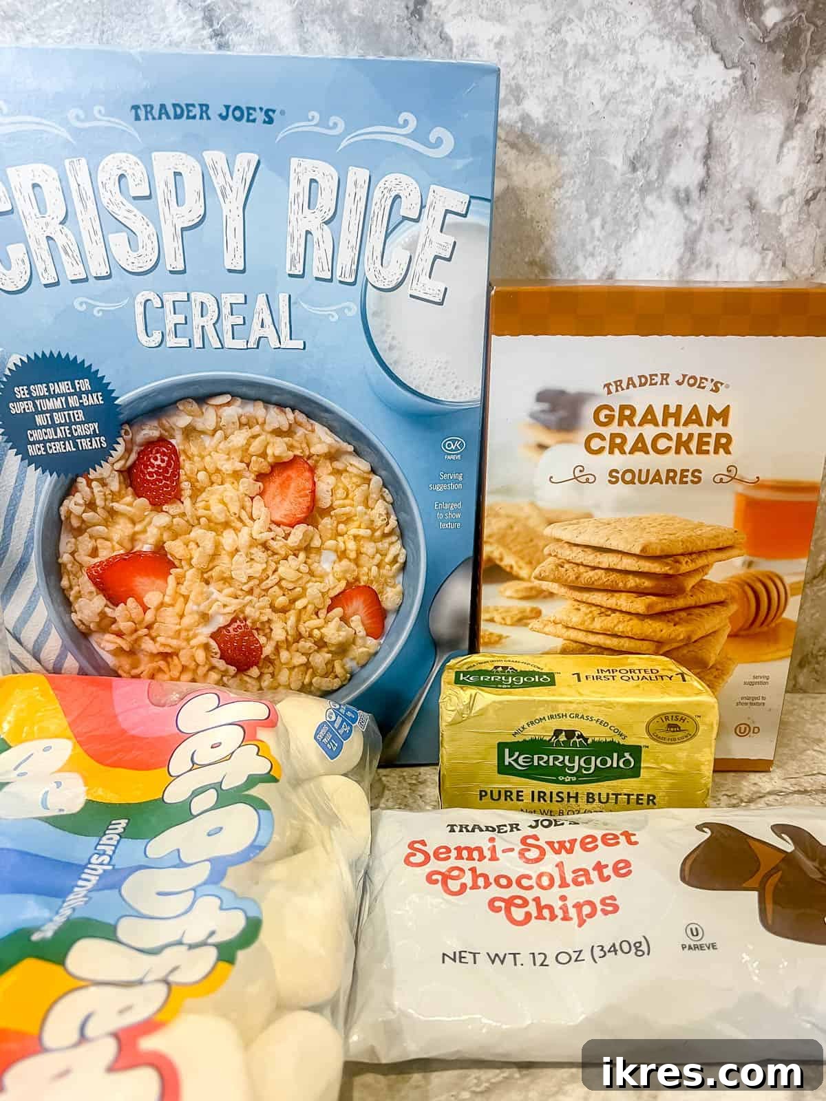 A visually appealing flat lay of all the essential ingredients laid out for making S'mores Rice Krispie Treats: crispy rice cereal, graham crackers, butter, marshmallows, and chocolate chips.