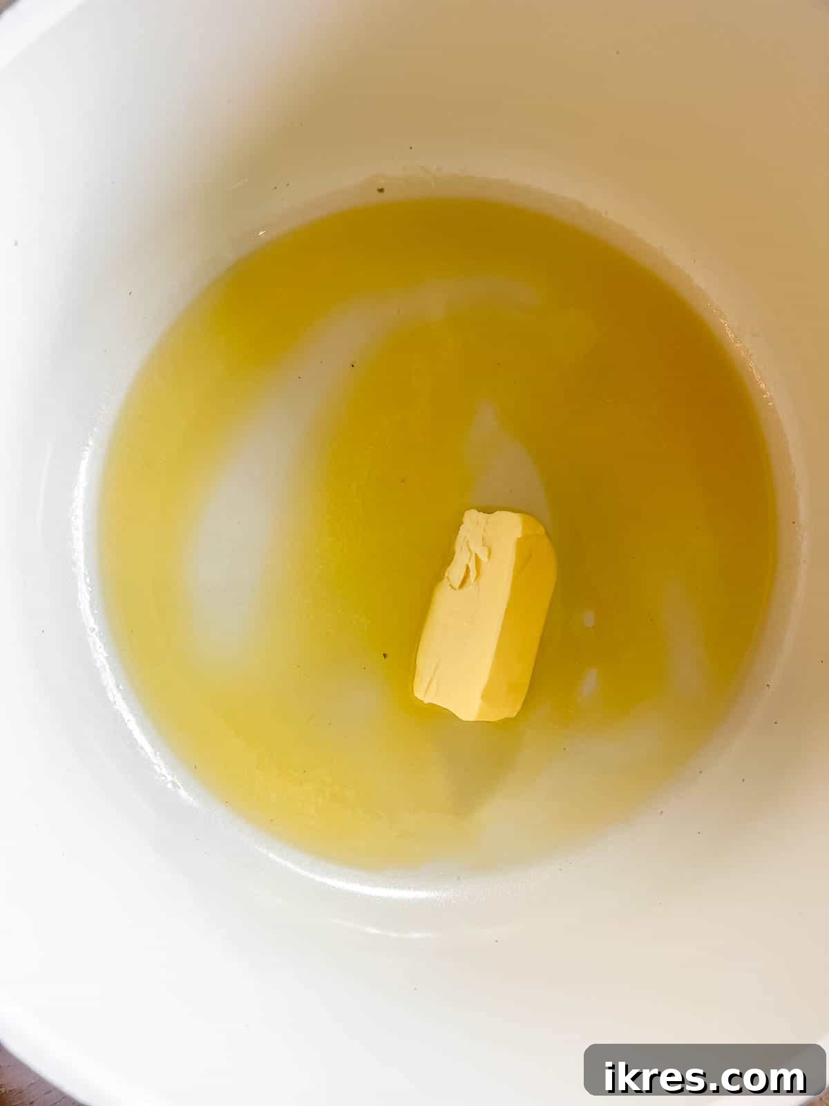 Three tablespoons of butter gently melting in a large saucepan over low heat, preparing for the marshmallow mixture.