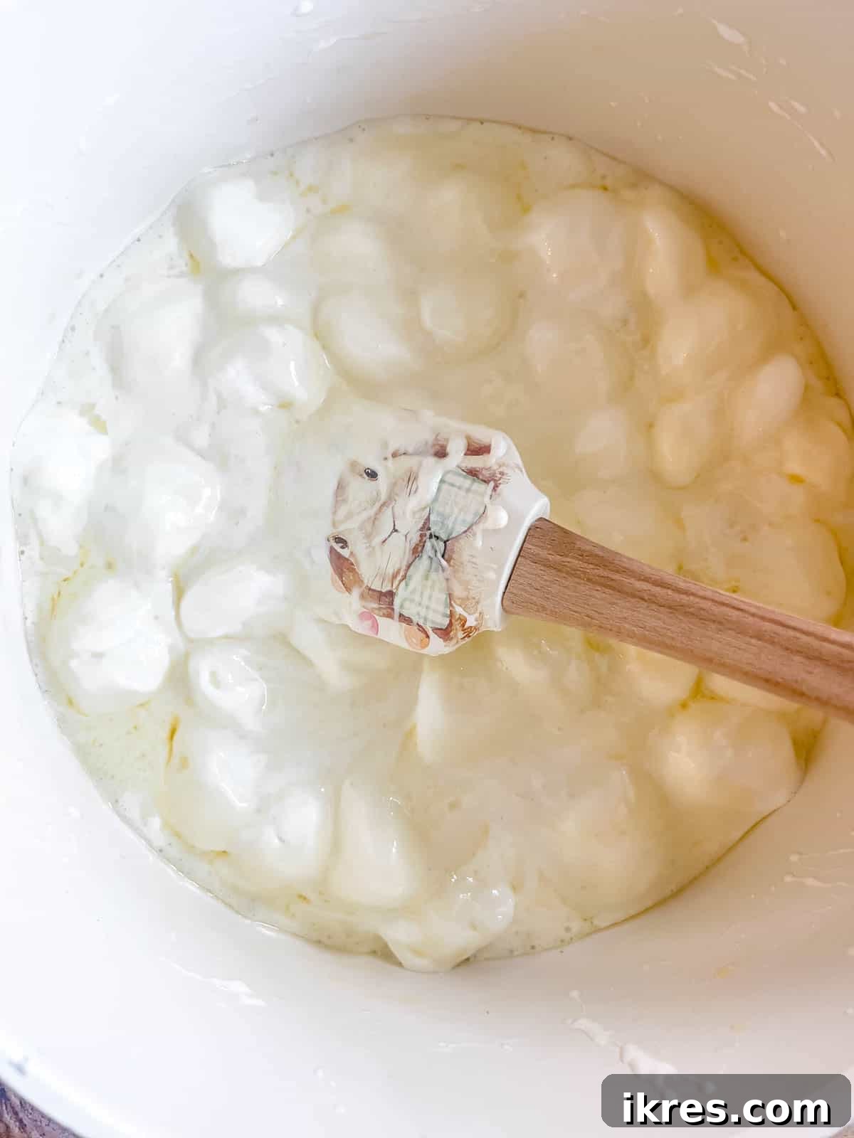 The marshmallows and butter are fully melted into a smooth, glossy, and golden mixture in the saucepan, ready to be combined with the dry ingredients.