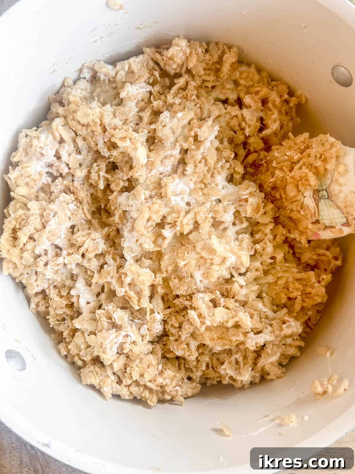 The crispy rice cereal and graham cracker crumbs are thoroughly mixed into the melted marshmallow and butter, creating a cohesive, sticky, and flavorful S'mores Rice Krispie base.