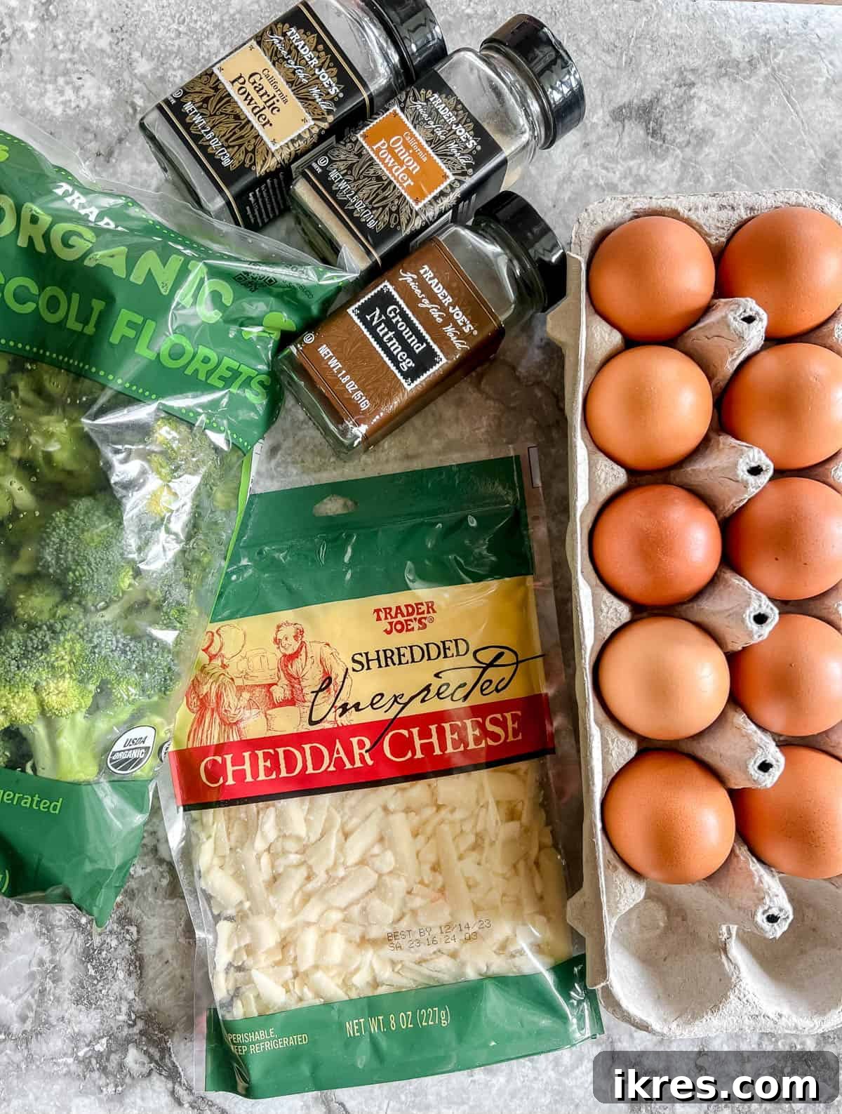 A collection of fresh ingredients for broccoli egg muffins, including eggs, broccoli florets, and shredded cheddar cheese, laid out on a wooden board.