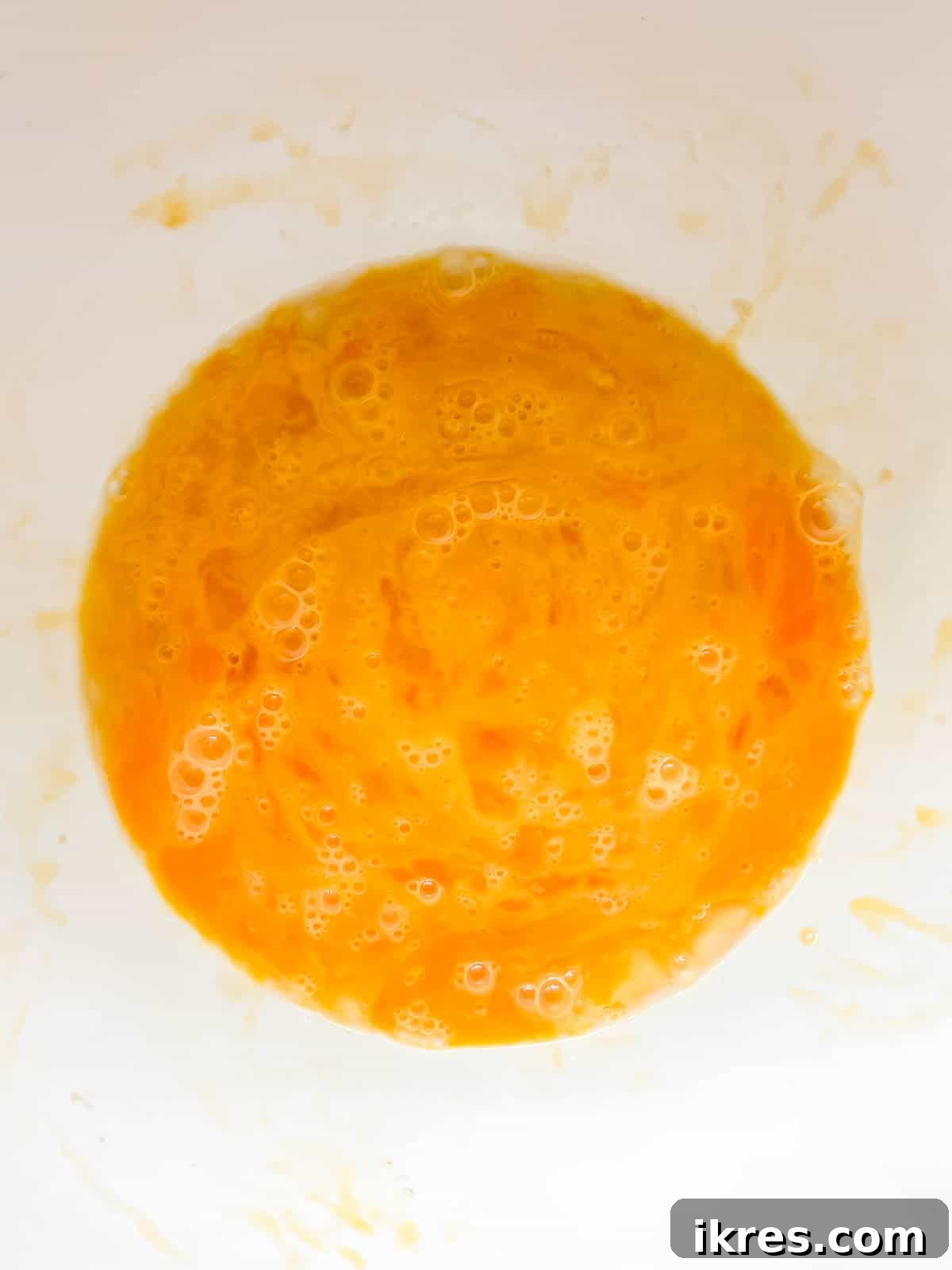 Ten large eggs cracked into a large mixing bowl and lightly whisked.