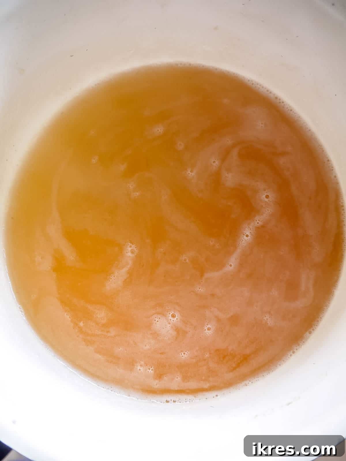 DIY Apple Gummy Delights 5 Apple juice and maple syrup heating in a saucepan on the stovetop.