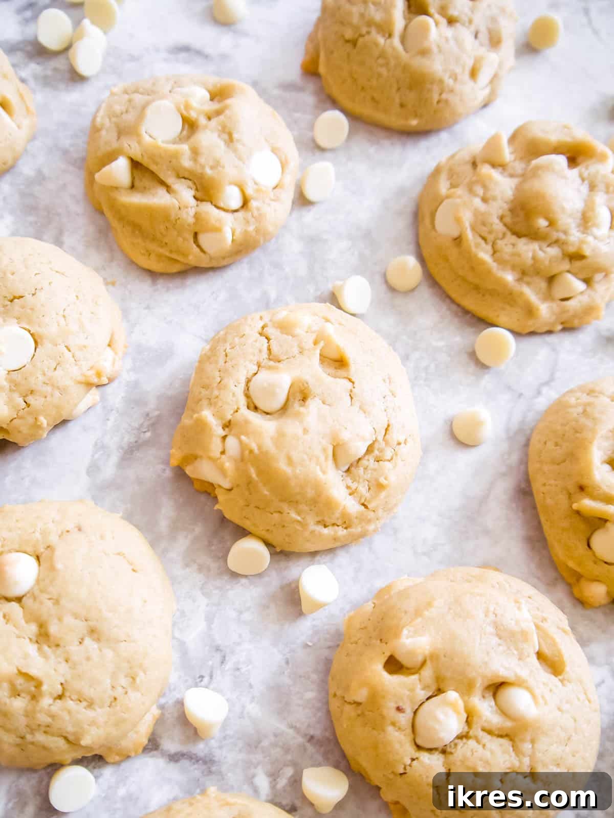 Deliciously soft and chewy white chocolate chip cookies artfully arranged with loose white chocolate chips around them, ready to be enjoyed.