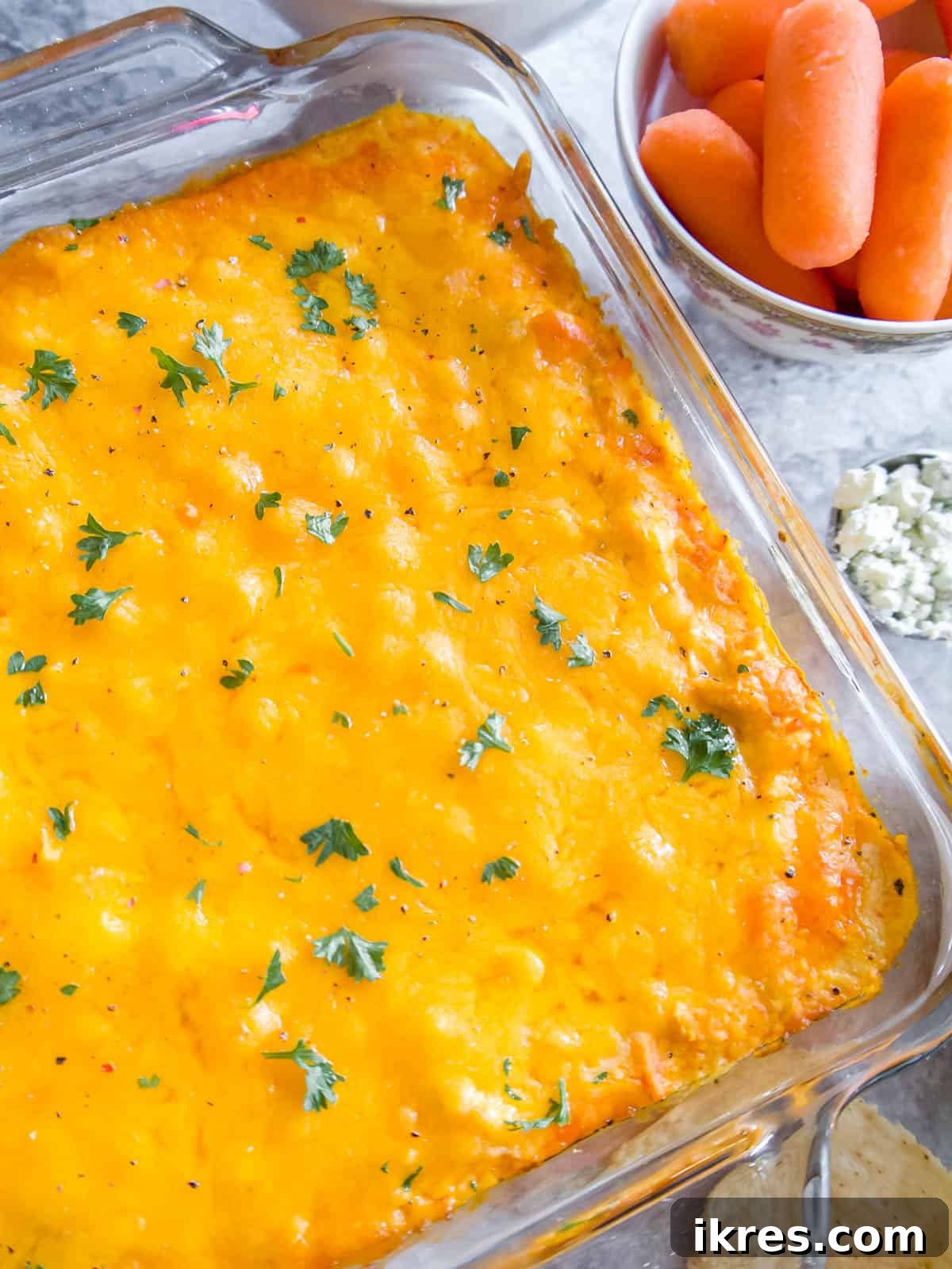 Close-up of baked buffalo chicken dip covered in melted cheddar cheese, ready to be scooped.