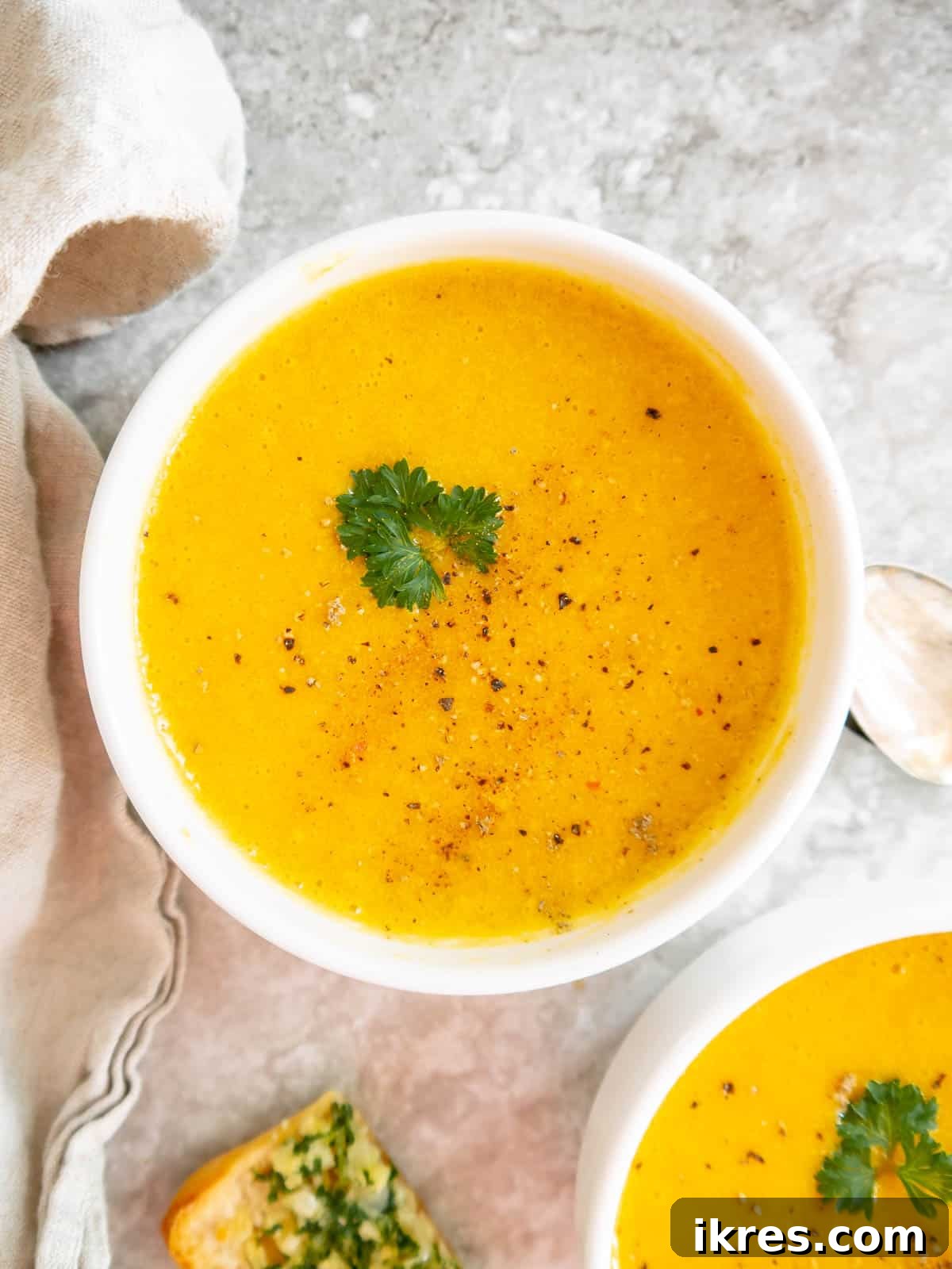 Roasted butternut squash soup in two bowls with parsley on top.